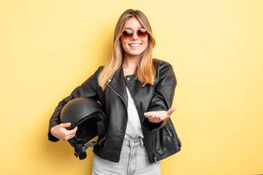 Güzel sarışın kız mutlu bir şekilde gülümsüyor ve bir konsept sunuyor. Motosiklet kaskı konsepti