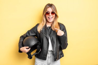 Güzel sarışın kız mutlu hissediyor ve heyecanla kendini işaret ediyor. Motosiklet kaskı konsepti