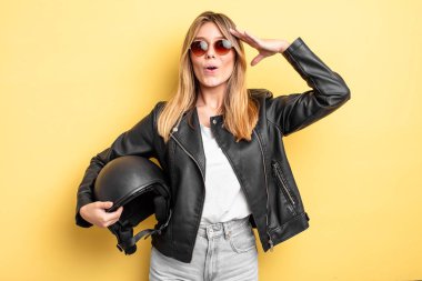 Güzel sarışın kız mutlu, şaşkın ve şaşırmış görünüyor. Motosiklet kaskı konsepti