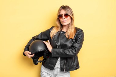 Güzel sarışın kız omuz silkiyor, kafası karışık ve kararsız. Motosiklet kaskı konsepti