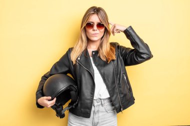 Güzel sarışın kız şaşkın ve şaşkın hissediyor, senin deli olduğunu gösteriyor. Motosiklet kaskı konsepti