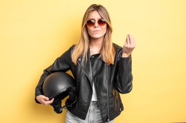 Güzel sarışın kız kapiş ya da para hareketi yapıyor, sana ödemeni söylüyor. Motosiklet kaskı konsepti