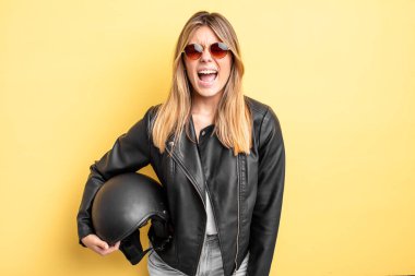 Güzel sarışın kız agresif bir şekilde bağırıyor, çok kızgın görünüyor. Motosiklet kaskı konsepti