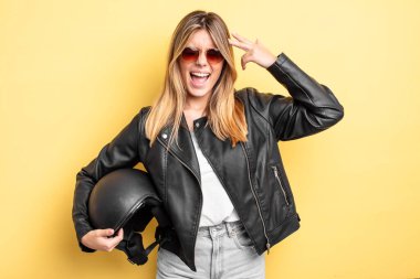 Güzel sarışın kız mutsuz ve stresli görünüyor, intihar jesti silah işareti yapıyor. Motosiklet kaskı konsepti