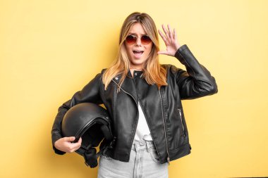 Güzel sarışın kız ellerini havaya kaldırarak çığlık atıyor. Motosiklet kaskı konsepti