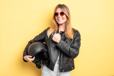 Güzel sarışın kız kendini mutlu hissediyor ve bir meydan okumayla yüzleşiyor ya da kutluyor. Motosiklet kaskı konsepti