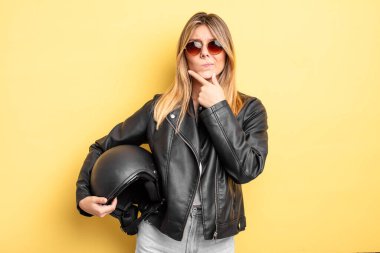 Güzel sarışın kız düşünüyor, kuşkulu ve şaşkın hissediyor. Motosiklet kaskı konsepti