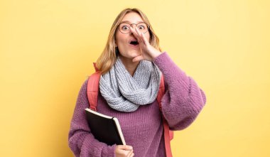 Güzel sarışın kız kendini mutlu hissediyor, elleri ağzının kenarında bağırıyor. öğrenci konsepti