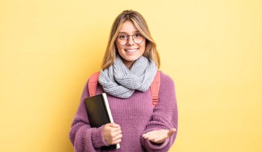 Güzel sarışın kız mutlu bir şekilde gülümsüyor ve bir konsept sunuyor. öğrenci konsepti