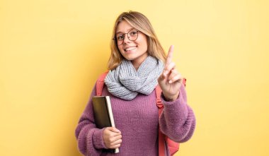 Güzel sarışın kız gururla gülümsüyor ve kendinden emin bir numara oluyor. öğrenci konsepti