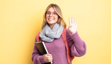 Güzel sarışın kız gülümsüyor ve arkadaş canlısı görünüyor, dört numarayı gösteriyor. öğrenci konsepti