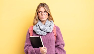 Güzel sarışın kız üzgün, üzgün ya da kızgın ve yana bakıyor. öğrenci konsepti