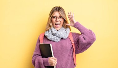 Güzel sarışın kız ellerini havaya kaldırarak çığlık atıyor. öğrenci konsepti