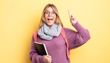 Güzel sarışın kız bir fikri fark ettikten sonra mutlu ve heyecanlı bir dahi gibi hissediyor. öğrenci konsepti