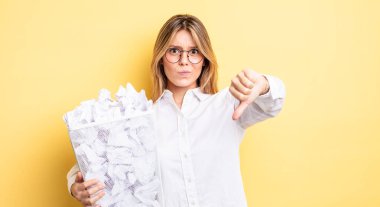 Güzel sarışın kız kendini kötü hissediyor, baş parmağını kaldırıyor. kağıt toplar çöp konsepti