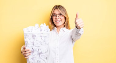 Güzel sarışın kız gururlu, olumlu gülümsüyor. kağıt toplar çöp konsepti