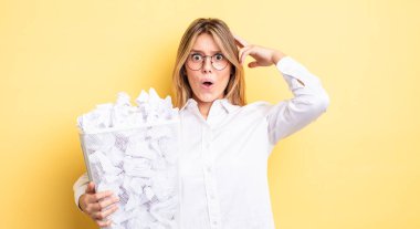 Güzel sarışın kız mutlu, şaşkın ve şaşırmış görünüyor. kağıt toplar çöp konsepti