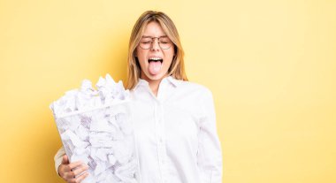 Güzel sarışın, neşeli ve asi tavırlı, şaka yapan ve dilini dışarı çıkaran bir kız. kağıt toplar çöp konsepti