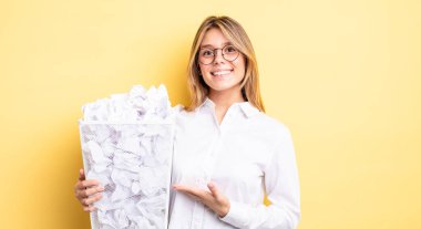 Güzel sarışın kız neşeyle gülümsüyor, mutlu hissediyor ve bir konsept gösteriyor. kağıt toplar çöp konsepti