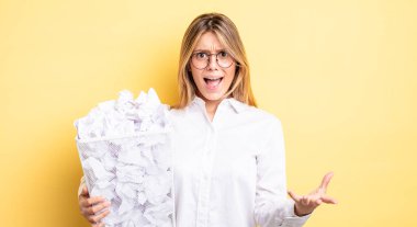 Güzel sarışın kız sinirli, sinirli ve sinirli görünüyor. kağıt toplar çöp konsepti