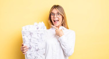 Güzel sarışın kız heyecanlı ve şaşırmış görünüyor. kağıt toplar çöp konsepti