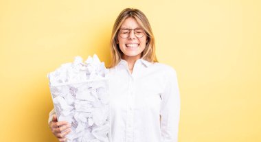 Güzel sarışın kız agresif bir şekilde bağırıyor, çok kızgın görünüyor. kağıt toplar çöp konsepti