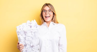 Güzel sarışın kız mutlu ve hoş bir şekilde şaşırmış görünüyor. kağıt toplar çöp konsepti
