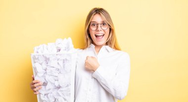 Güzel sarışın kız kendini mutlu hissediyor ve bir meydan okumayla yüzleşiyor ya da kutluyor. kağıt toplar çöp konsepti