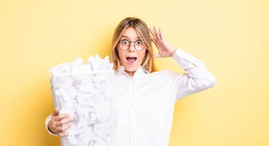 Güzel sarışın kız ellerini havaya kaldırarak çığlık atıyor. kağıt toplar çöp konsepti