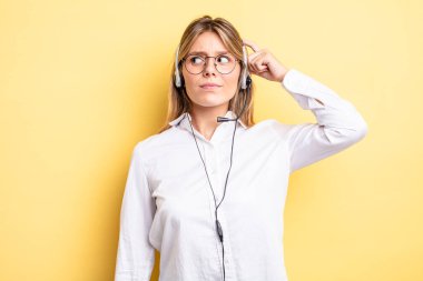 Güzel sarışın kız mutlu bir şekilde gülümsüyor ve hayal kuruyor ya da şüphe ediyor. kulaklık konsepti