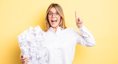 Güzel sarışın kız bir fikri fark ettikten sonra mutlu ve heyecanlı bir dahi gibi hissediyor. kağıt toplar çöp konsepti