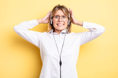 Güzel sarışın kız stresli, endişeli ya da korkmuş, elleri başının üstünde. kulaklık konsepti