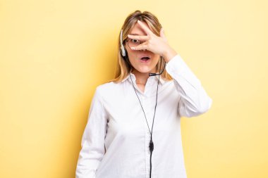 Güzel sarışın kız şok olmuş, korkmuş ya da korkmuş görünüyor. Yüzü elle kapatılmış. kulaklık konsepti