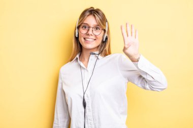 Güzel sarışın kız gülümsüyor ve arkadaş canlısı görünüyor, dört numarayı gösteriyor. kulaklık konsepti