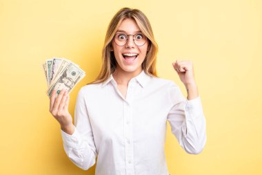 Güzel sarışın kız şokta, gülüyor ve başarıyı kutluyor. Dolar banknotları konsepti