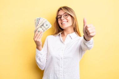 Güzel sarışın kız gururlu, olumlu gülümsüyor. Dolar banknotları konsepti