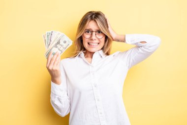 Güzel sarışın kız stresli, endişeli ya da korkmuş, elleri başının üstünde. Dolar banknotları konsepti