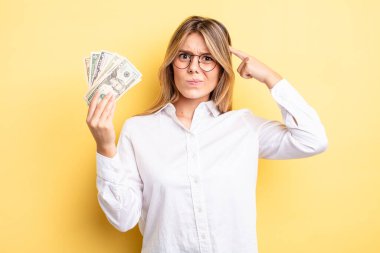 Güzel sarışın kız şaşkın ve şaşkın hissediyor, senin deli olduğunu gösteriyor. Dolar banknotları konsepti