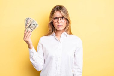 Güzel sarışın kız üzgün, üzgün ya da kızgın ve yana bakıyor. Dolar banknotları konsepti