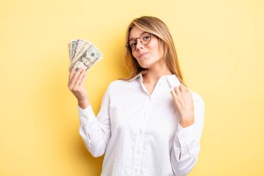 Güzel sarışın kız kibirli, başarılı, pozitif ve gururlu görünüyor. Dolar banknotları konsepti