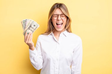 Güzel sarışın kız agresif bir şekilde bağırıyor, çok kızgın görünüyor. Dolar banknotları konsepti