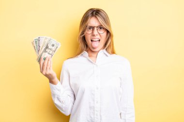 Güzel sarışın kız iğreniyor, sinirleniyor ve dilini çıkarıyor. Dolar banknotları konsepti