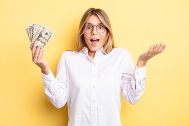 Güzel sarışın kız şok olmuş ve şaşırmış hissediyor. Dolar banknotları konsepti