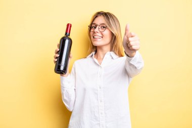 Güzel sarışın kız gururlu, olumlu gülümsüyor. şarap şişesi konsepti