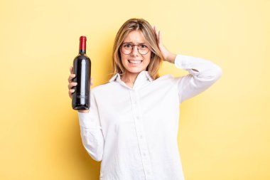 Güzel sarışın kız stresli, endişeli ya da korkmuş, elleri başının üstünde. şarap şişesi konsepti