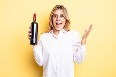Güzel sarışın kız kendini mutlu hissediyor ve inanılmaz bir şeye hayret ediyor. şarap şişesi konsepti