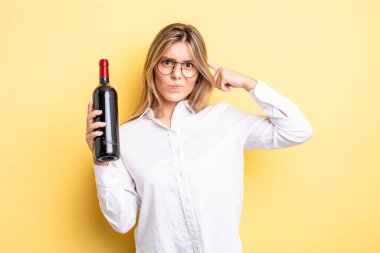 Güzel sarışın kız şaşkın ve şaşkın hissediyor, senin deli olduğunu gösteriyor. şarap şişesi konsepti