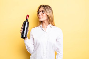 Profil görünümündeki güzel sarışın kız hayal mi kuruyor, hayal mi kuruyor yoksa hayal mi kuruyor? şarap şişesi konsepti