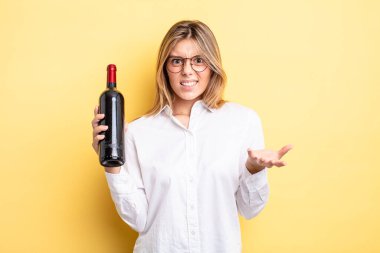 Güzel sarışın kız sinirli, sinirli ve sinirli görünüyor. şarap şişesi konsepti