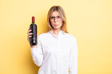 Güzel sarışın kız üzgün ve mızmızlanıyor. Mutsuz bir bakışı var ve ağlıyor. şarap şişesi konsepti